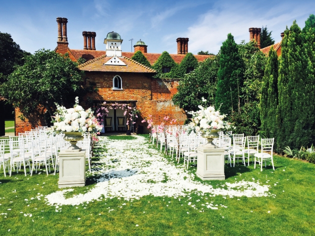 Woodhall Manor, outside ceremony white chairs on lawn in front of red brick building