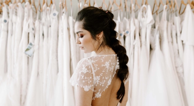 model in wedding dress in front of dress rack