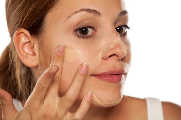 young beautiful woman applying foundation on her face