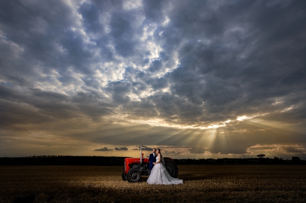 couple in field at dusk standing in front of tractor