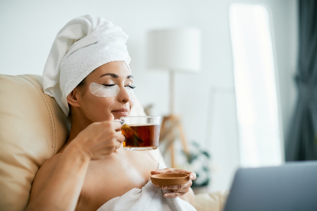 woman in bath tub with tea and eye mask