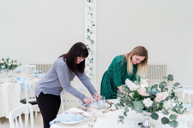 two wedding planners setting up a table
