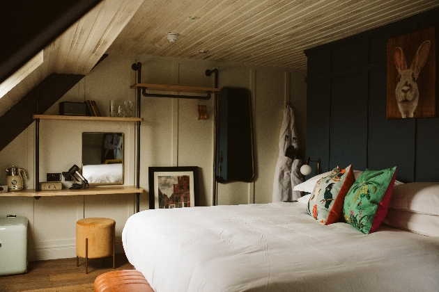 bedroom with wood panelled walls, industrial style furniture and a large bed with white sheets