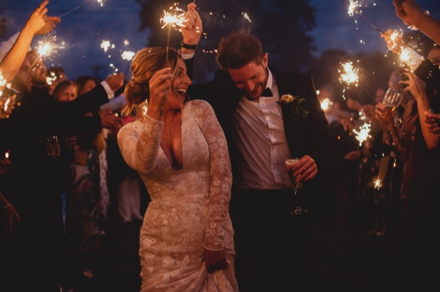 bride and groom walking through a sparkler arch