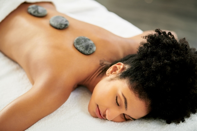 woman on bed with hot stones on her back