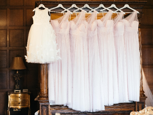 a row of pink bridesmaids dressing all matching hanging on a wardrobe