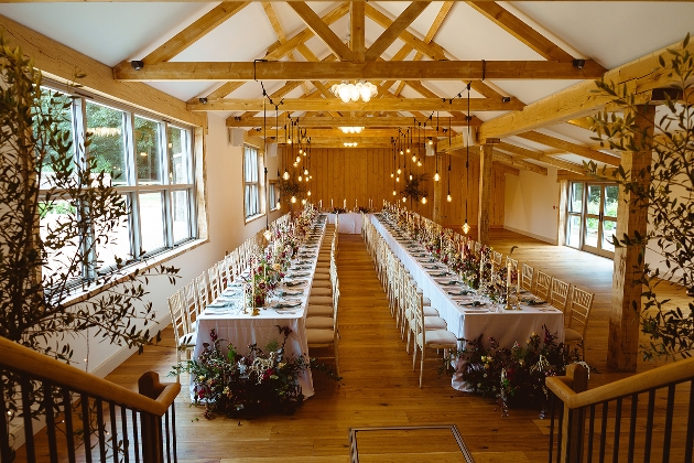 interior of barn with exposed beams and long straight tables dressed for a wedding