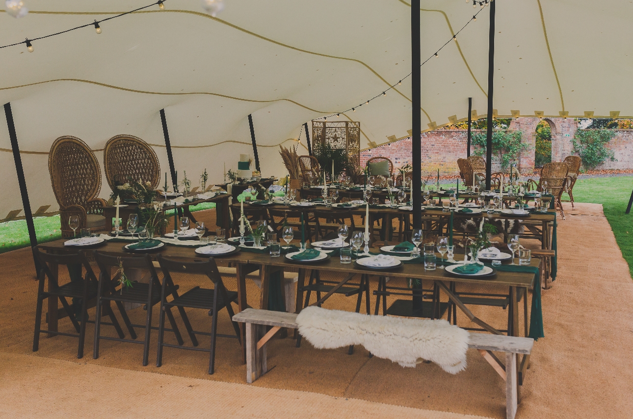 tip with wooden trestle tables set up for a wedding, with a rustic boho vibe