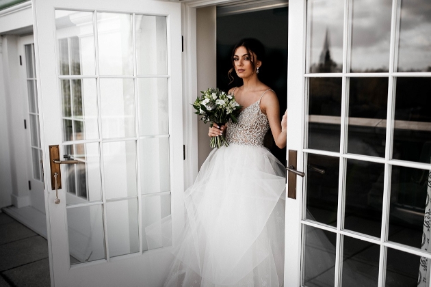 model in wedding dress walking through glass doors