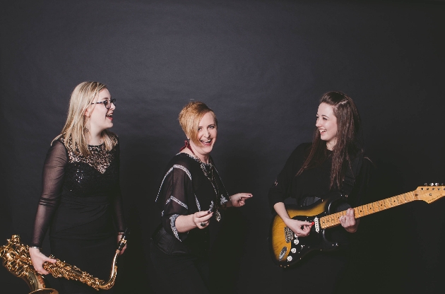 three female band members with instruments