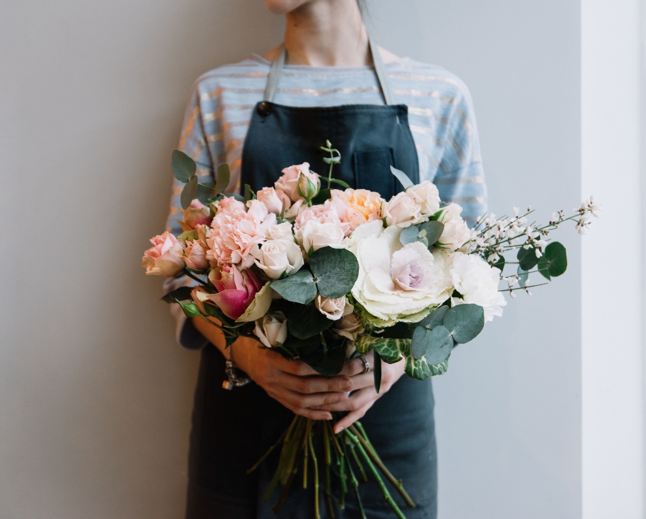 florist in apron holding bouquet of flowers