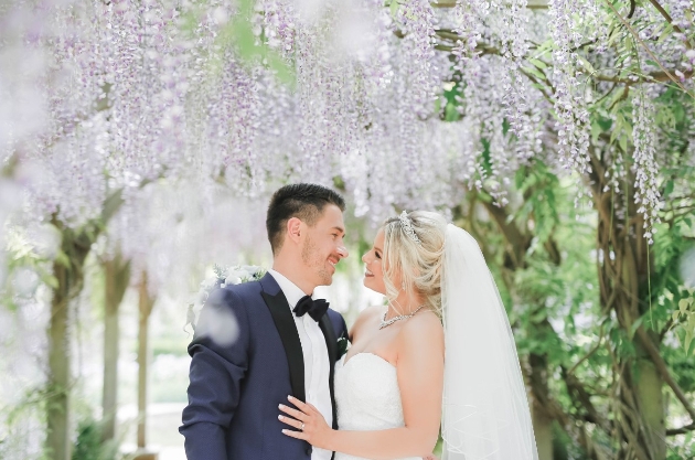 bride and groom standing under blossom tree