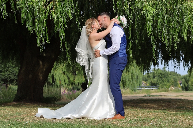 bride and groom embracing outdoors under weeping willow