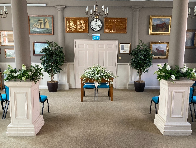 ceremony room grey walls and pillars flowers round the bases
