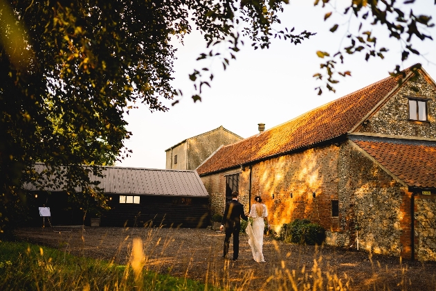 Bride and groom walking hand-in-hand outside Curds Hall Barn