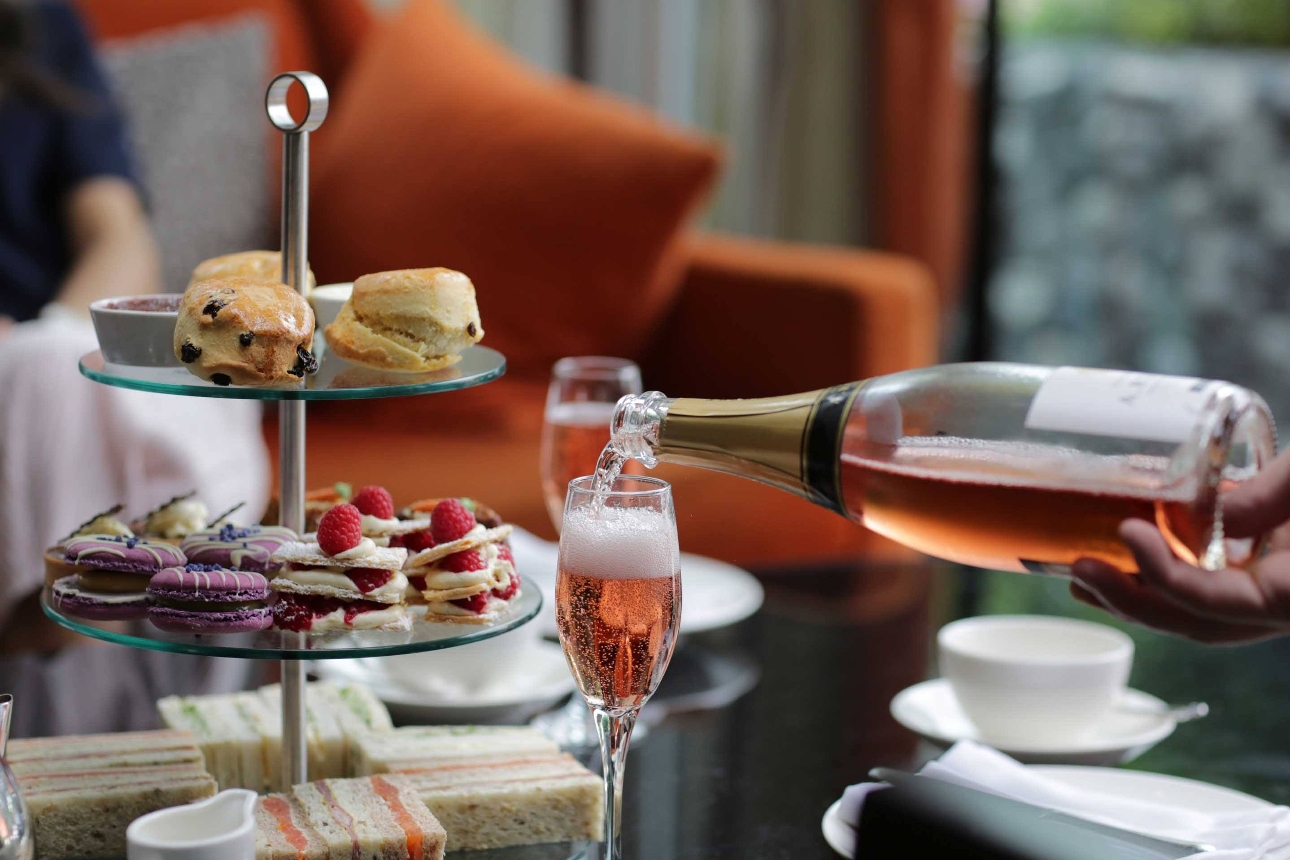 afternoon tea with sandwiches, cake, and fizz on table