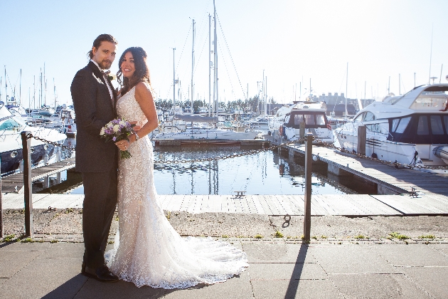 Bride and groom standing in front of a few boats