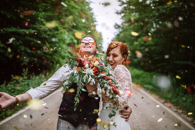 Bride and groom laughing while surrounded by confetti