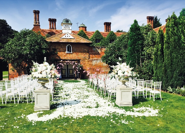 An outdoor wedding ceremony with white flower petals in between the chairs