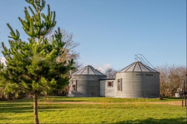 The exterior of a large tin building surrounded by grass