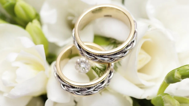 Two gold and silver rings sitting on a bunch of white roses