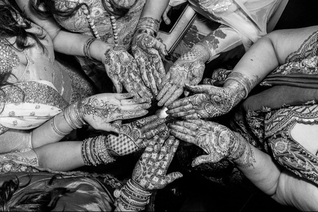 group of hands in a circle with henna on