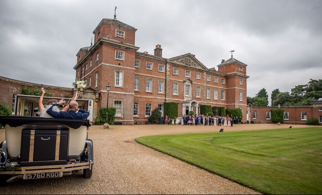 historic mansion with lawn, couple arriving in vintage car