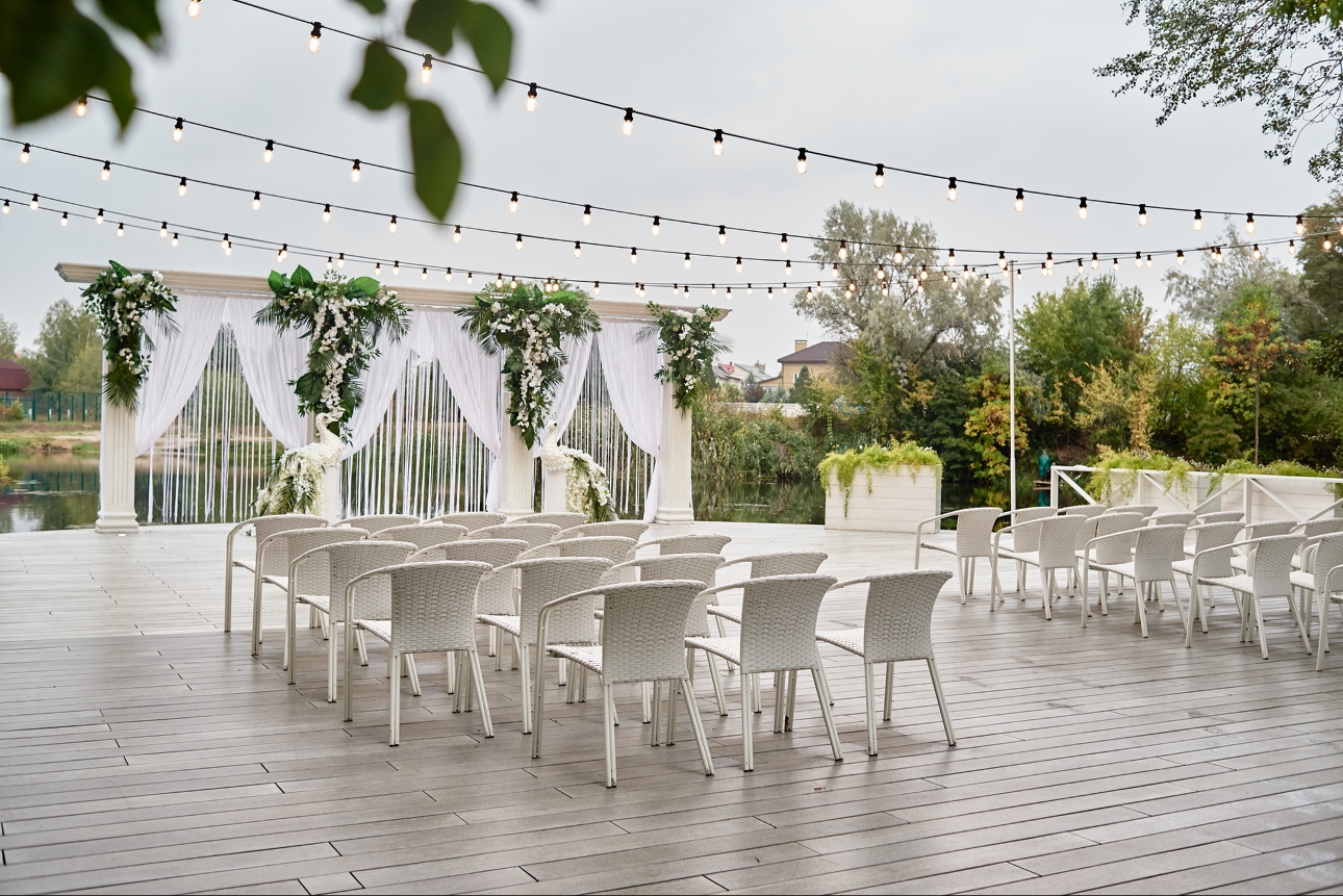 white ceremony chairs set up on decking outside looking at a ceremony area