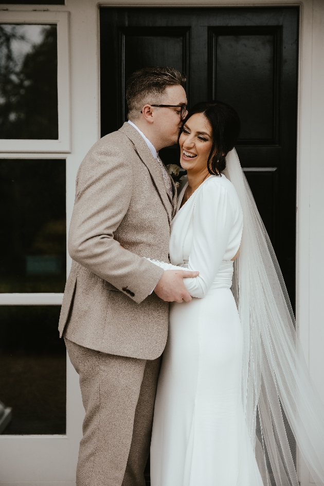 A bride and groom embracing in front of a black door