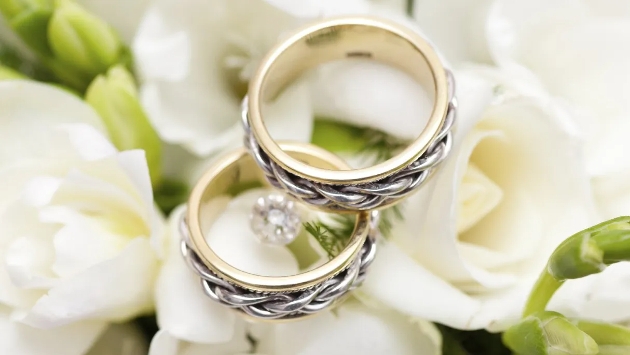 Two wedding rings sitting on a bed of white flowers
