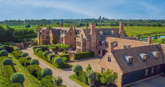 The exterior of a grand manor surrounded by green gardens