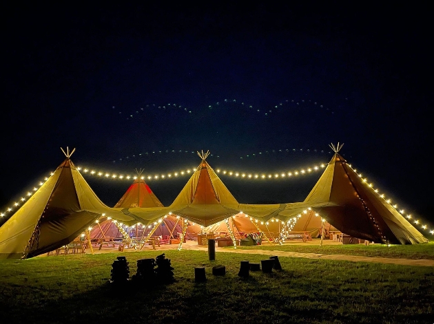 A giant tipi decorated with fairylights at night