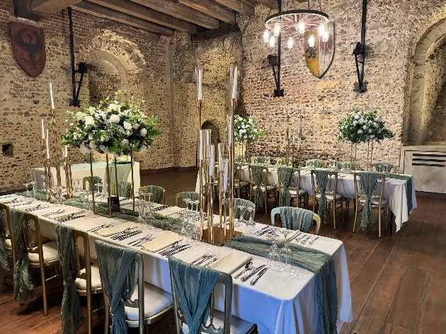 A large stone room with two tables in decorated with flowers and candles