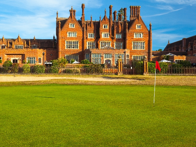 A grand manor house with a golf course in front of it