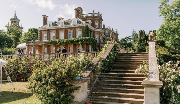 A large manor house decorated in beautiful flowers with large steps next to the property