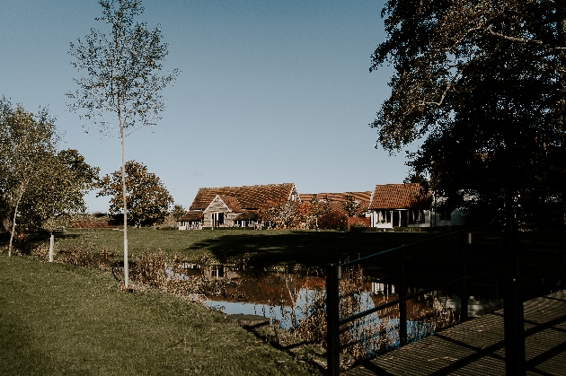 The exterior of a barn with a large pond in front of it