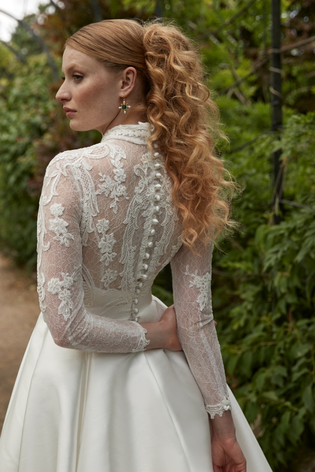 woman with curly hair posing in long-sleeve lace dress