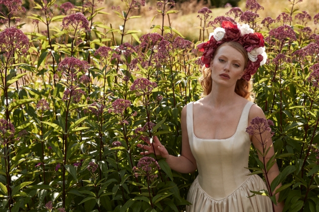 woman wearing large flower crown posing in flower field 