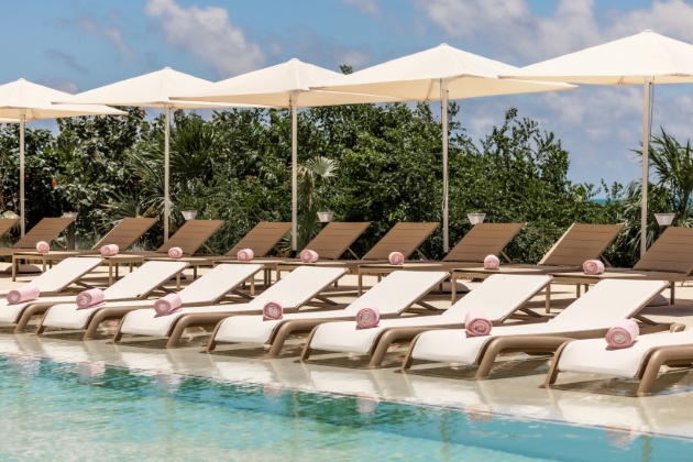 pool side image with pink towels rolled up on sunbeds
