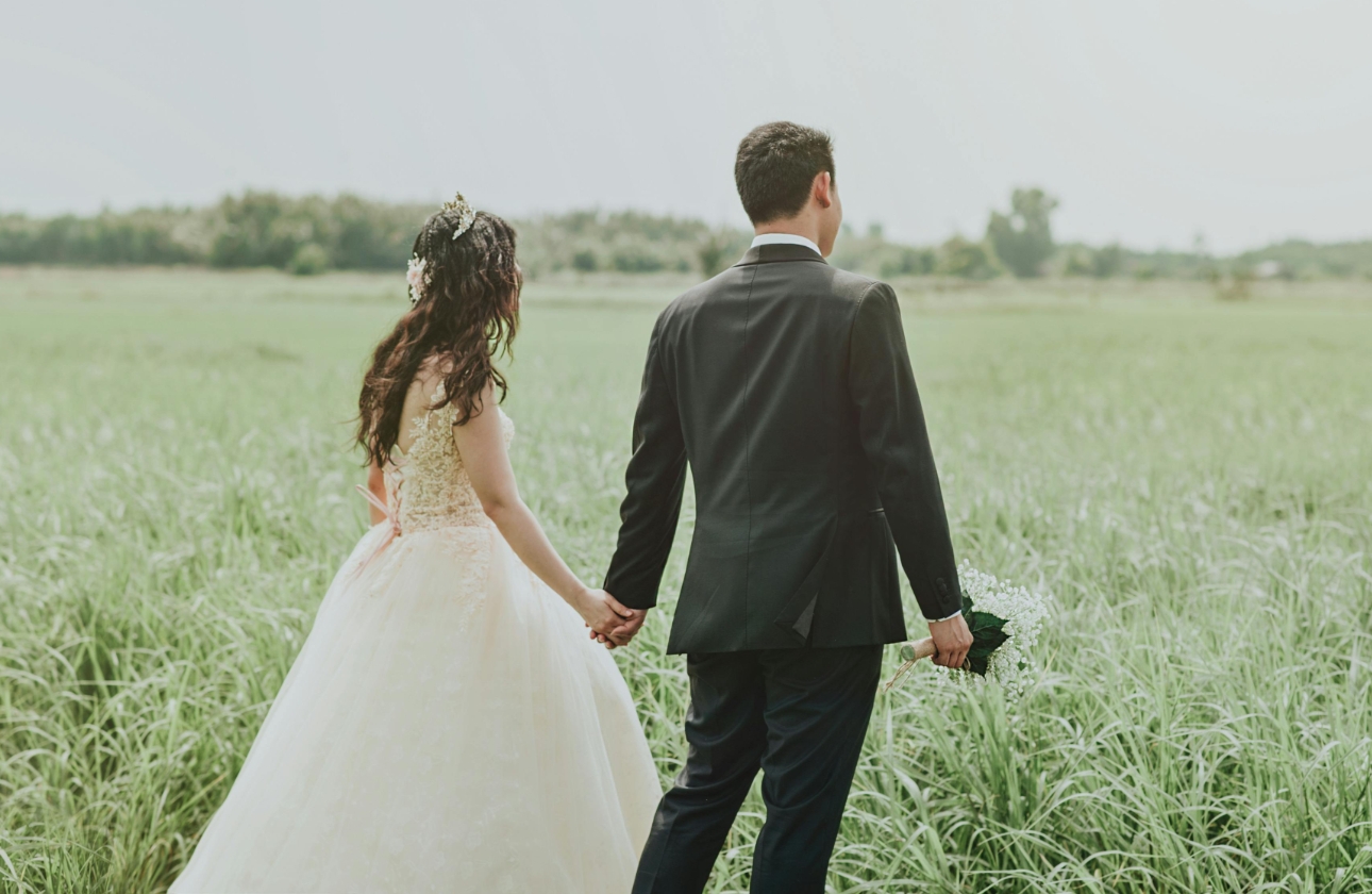 couple wedded outside walking through a field
