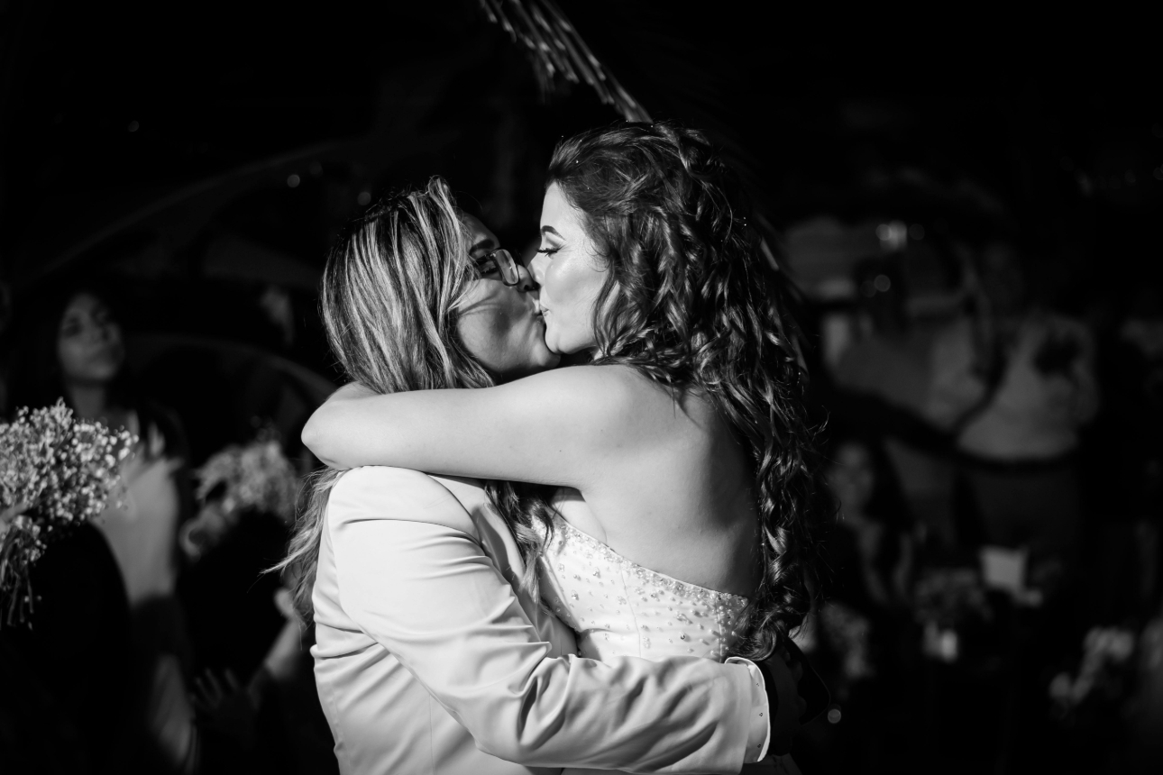 two bride kissing on dancefloor in black and white image