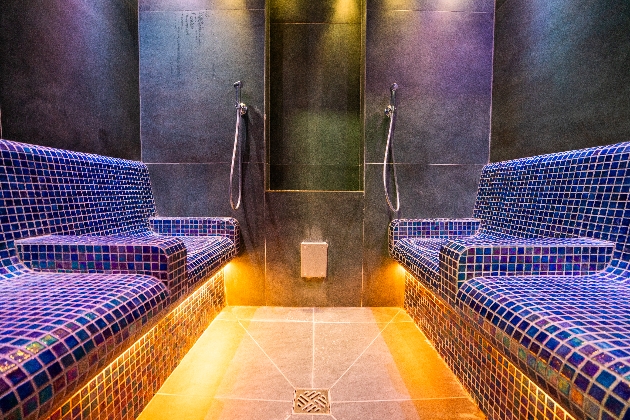 The inside of a sauna with blue and white mosaic chairs