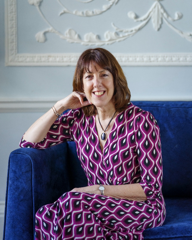 Heather Bartsch smiling at the camera wearing a purple patterned dress