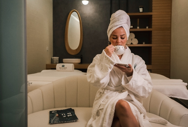 A woman drinking a drink in a robe at a spa