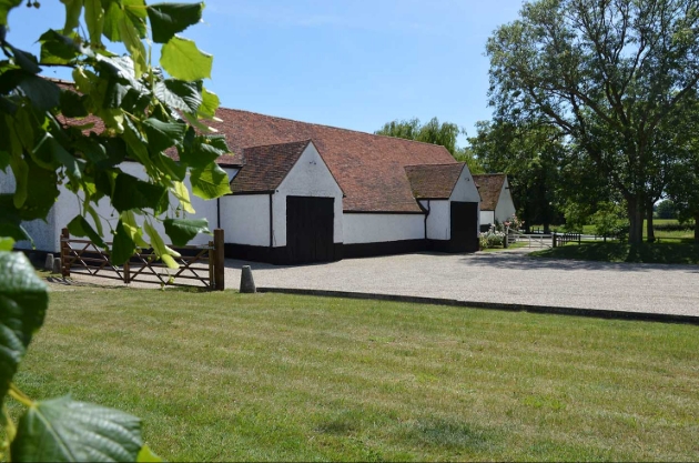 The exterior of a white barn with a red brick roof