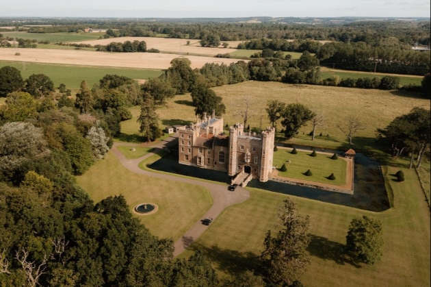 A sky view of a castle surrounded by lush grounds