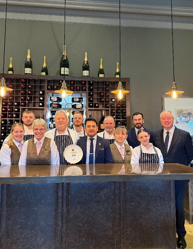 People behind a bar holding an award
